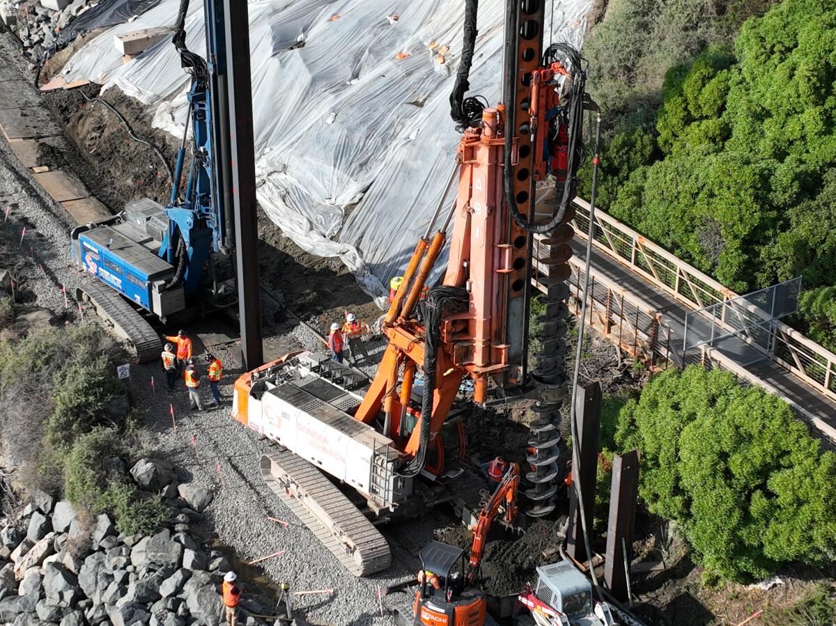 Protective tarping is placed to prevent further slides from upcoming rain storms and crews building a barrier wall.