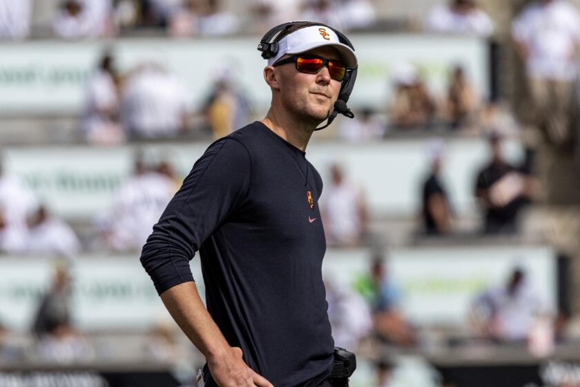 USC coach Lincoln Riley wears sunglasses, rests his hands on hips and looks at Colorado scoreboard during a tight game