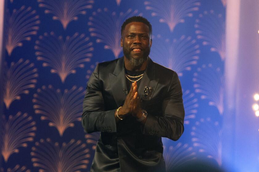 Kevin Hart claps his hand together onstage while accepting a prize