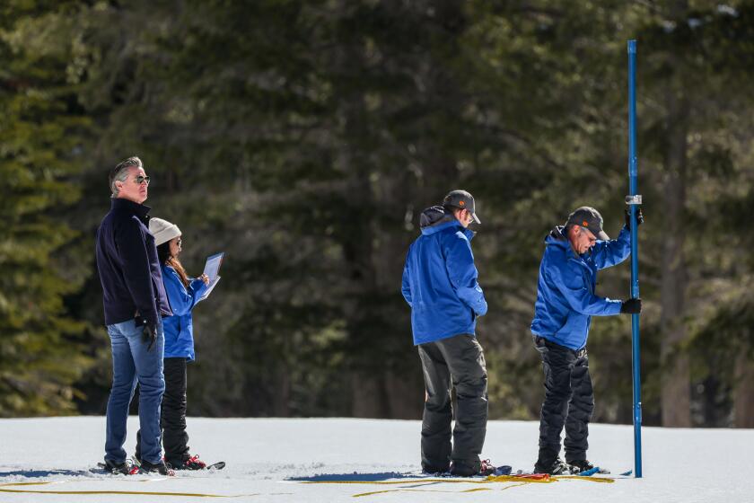 (Left to right) Gov. Gavin Newsom watches Angelique Fabbiani-Leon, State Hydrometeorologist, Water Resources Engineers Anthony Burdock and Andy Reising during the fourth media snow survey of the 2024 seasonis held at Phillips Station in the Sierra Nevada.The survey is held approximately90 miles east of Sacramento off Highway 50 in El Dorado County.Photo taken April 2, 2024. (Andrew Nixon / California Department of Water Resources)