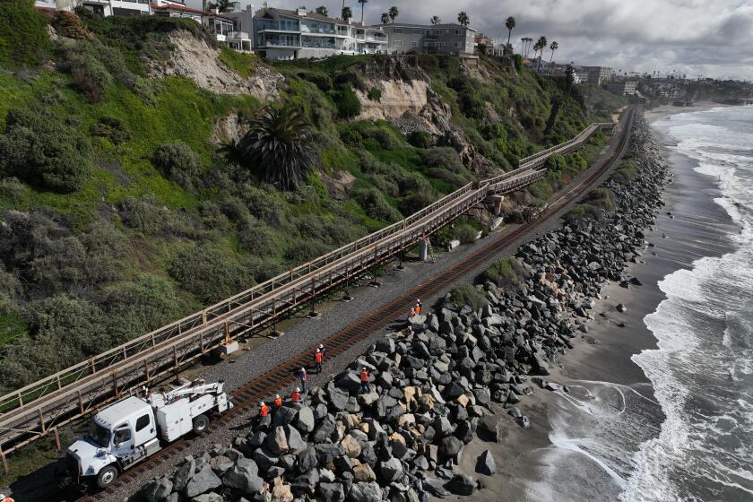 San Clemente, CA - January 25: An aerial view of Metrolink workers surveying a landslide that partially covered the train tracks and damage the Mariposa Trail Bridge, north of the San Clemente Pier in San Clemente Thursday, Jan. 25, 2024. Passenger rail service between the Laguna Niguel/Mission Viejo and Oceanside stations was suspended due to boulders and debris falling onto the tracks caused by a landslide damaging the Mariposa Trail Bridge in San Clemente, Metrolink announced, and it was uncertain today when service would resume. (Allen J. Schaben / Los Angeles Times)