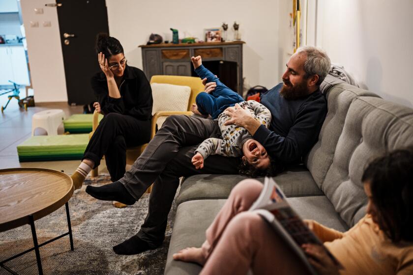 HAIFA, ISRAEL -- JANUARY 22, 2024: Carmel Neta and his wife Inbal, 36, spend time with both their children, Dror, 2, and Lily, 7, at home in Haifa, Israel, Monday, Jan. 22, 2024. Carmel Neta lost his mother Adrienne, 66, who was killed in the massacre at kibbutz BeOeri N one of about 1,200 people killed across the country that day in the single deadliest attack in IsraelOs history. A native Californian, Adrienne believed different cultures could and should co-exist. She had raised her four children to respect Palestinians, and had been deeply moved when Carmel and his wife had enrolled their two young children in an experimental bilingual school in which students from diverse backgrounds learned together in both Hebrew and Arabic. (MARCUS YAM / LOS ANGELES TIMES)