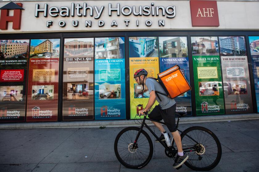 Los Angeles, CA - September 07: (**NOTE: This image is to be used for a specific story by Liam Dillon.) A cyclist rides past the Healthy Housing Foundation AHF located on Sunset Blvd. in Hollywood on Thursday, Sept. 7, 2023, in Los Angeles, CA. (Francine Orr / Los Angeles Times)