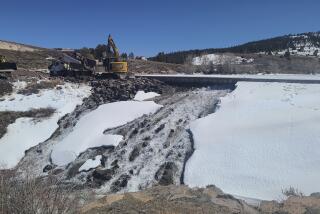 In this photo provided by the Utah Division of Water Rights, crews use heavy machinery to place boulders downstream of the cracked Panguitch Lake Dam to reinforce the wall, Wednesday, April 10, 2024, in Panguitch, Utah. (Matt Call/Utah Division of Water Rights via AP)