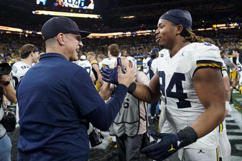 Michigan head coach Jim Harbaugh, left, celebrates with Michigan defensive lineman Kris Jenkins.