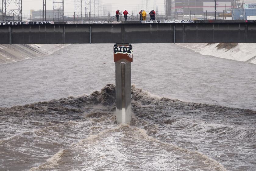 VERNON CA DECEMBER 14, 2021 - Los Angeles city fire swift water crews look down two vehicles in the Los Angeles River at the Washington Bridge near downtown Los Angeles. (Al Seib / Los Angeles Times)