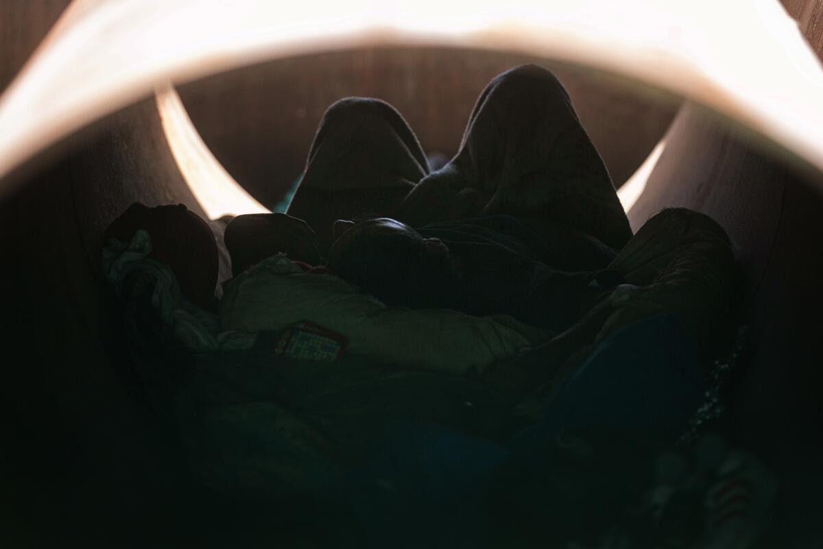 A homeless person sleeps in sewer pipe that the rail authority is storing on James Weirick's industrial site in Fresno.