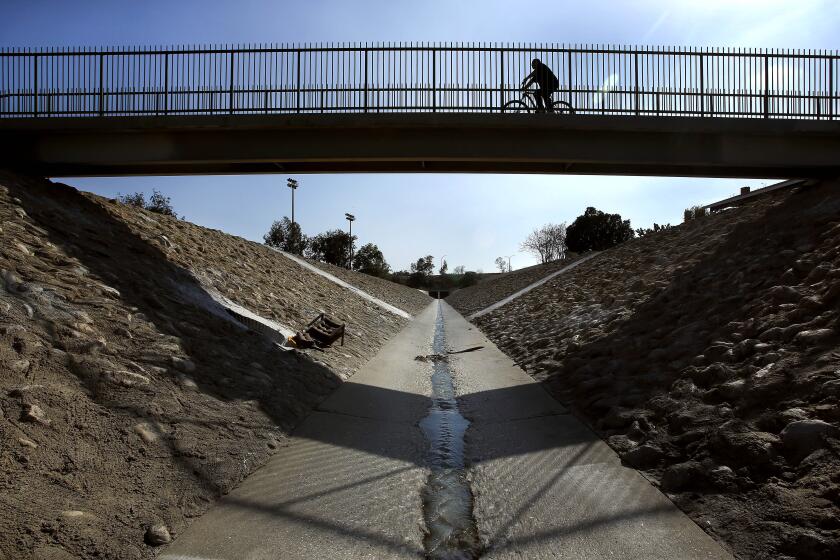 PACOIMA, CA-MARCH 21, 2014: A bicycle rider pedals across the Haddon Ave bridge located above the Pacoima Wash in Pacoima on March 21, 2014. City officials are considering ambitious plans to open up the area above the banks to the public, adding bike lanes and a "ribbon of green" to this densely-populated and park-poor area with high rates of obesity and health problems. (Mel Melcon/Los Angeles Times)