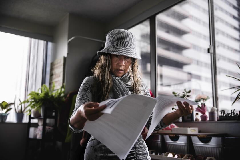 Josette Rojas, a tenant at Barrington Plaza, looks through an eviction notice on Monday, May 15, 2023