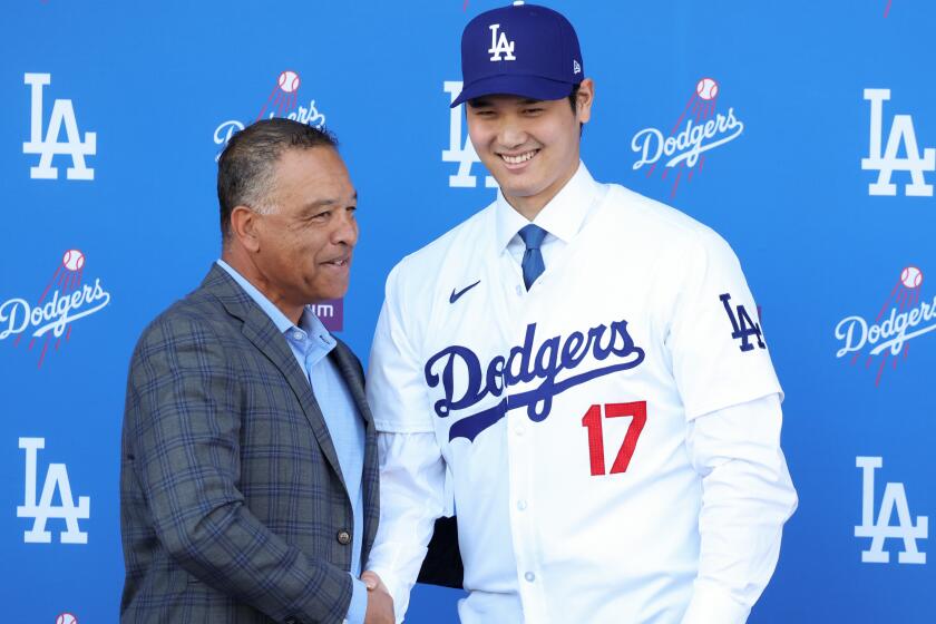 Dodgers manager Dave Roberts, left, shakes hands with Shohei Ohtani on Dec. 14, 2023.