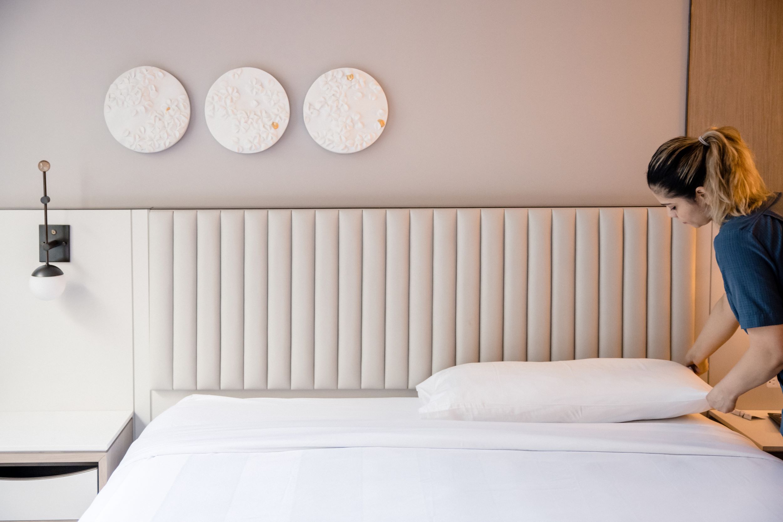 Housekeeper placing a pillow on a bed