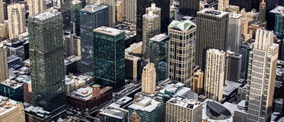 Aerial view of a dense urban cityscape with numerous high-rise buildings in various architectural styles.