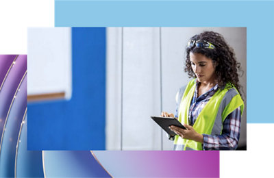 A person in a safety vest and safety glasses looking at a tablet