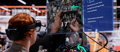 A technician wearing a virtual reality headset works on an electrical panel while referencing a digital overlay guide.
