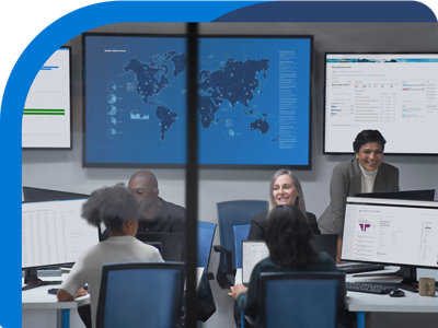 A group of people sitting at desks in front of monitors.