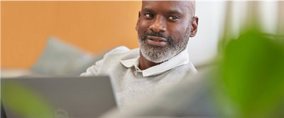 A person smiling with laptop placed in front of him