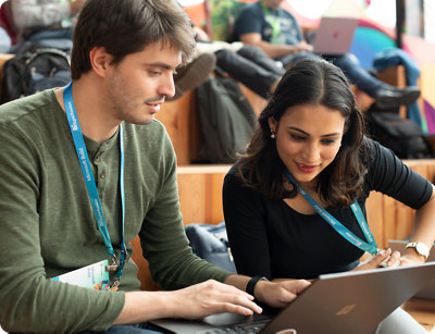  A man and woman sitting on a bench, focused on a laptop screen.