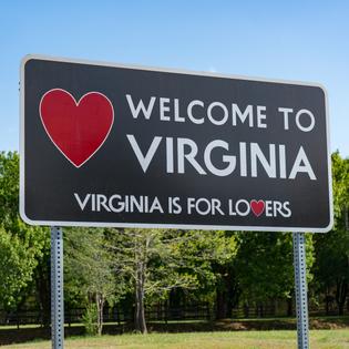 A roadside sign that says Welcome to Virginia and Virginia is for lovers with a red heart on the left-hand side.