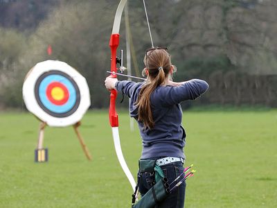 Archery. Woman pointing bow and arrow at target. (athlete; sports)