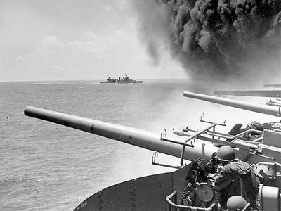 Battle of Midway. Midway Islands. (left of panorama asset 160828) USS Astoria (CA-34) steams by USS Yorktown (CV-5), shortly after the carrier had been hit by 3 Japanese bombs on June 4, 1942. Dense smoke is from fires in Yorktown's uptakes. (notes)