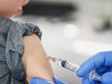 Young boy receiving a vaccine shot (child, vaccines, vaccinations, health care).