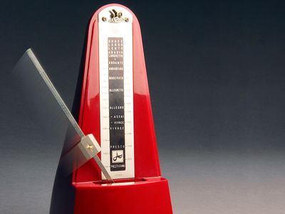 Metronome. Music. Tempo. Rhythm. Beats. Ticks.  Red metronome with swinging pendulum.