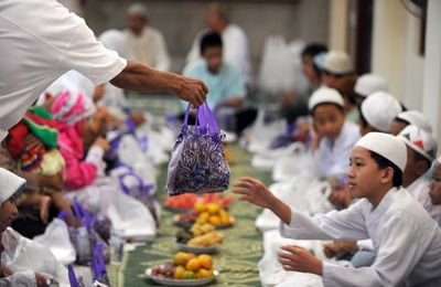 Indonesian Muslim children receive a bag of goods before Iftar meal or the breaking of the fast consisting of fruit, rice cakes, doughnuts, tea and water that comes with gifts for the children at Darussalam mosque in central Jakarta on September 5, 2010 as Muslims worldwide prepare for festivities marking the end of the fasting month of Ramadan and ushering the Eid al-Fitr festival. Indonesia is the world's most populous Muslim majority country.