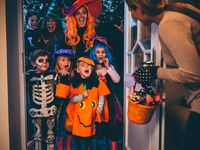 Group of children and their parents playing trick or treat on Halloween.