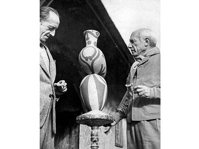 Pablo Picasso (right) with M. Ramier, owner of the Vallauris Pottery, shown viewing one of Picasso's pottery designs. 1948.