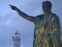 Statue of of the Roman emperor Nero with the lighthouse in the background at Anzio, Lazio region, Italy