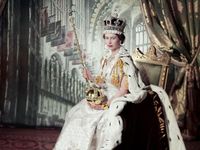 Queen Elizabeth II on her Coronation Day (June 2, 1953) holding the Sovereign's Sceptre with Cross in her right hand the Orb in her left, in an embroidered and beaded dress by Norman Hartnell, a crimson velvet mantle edged with ermine fur, with the Coronation ring, the Coronation necklace, and the Imperial State Crown. The backdrop depicts the interior of Westminster Abbey; photograph by Cecil Beaton. (British royals)