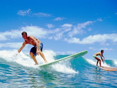 Surfers balance on surfboards as they ride a breaking wave.