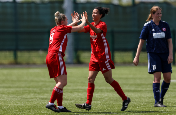 Two female footballers in red kit high-five