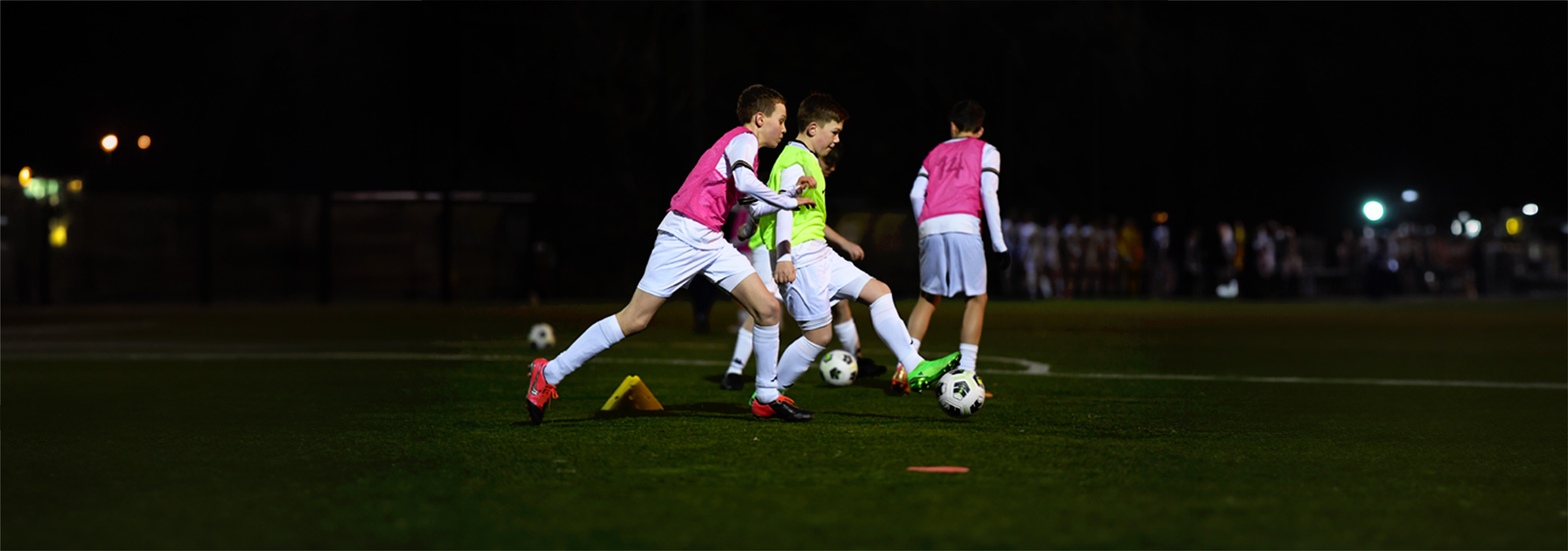 A couple of players run with a ball in training while under pressure from defenders.