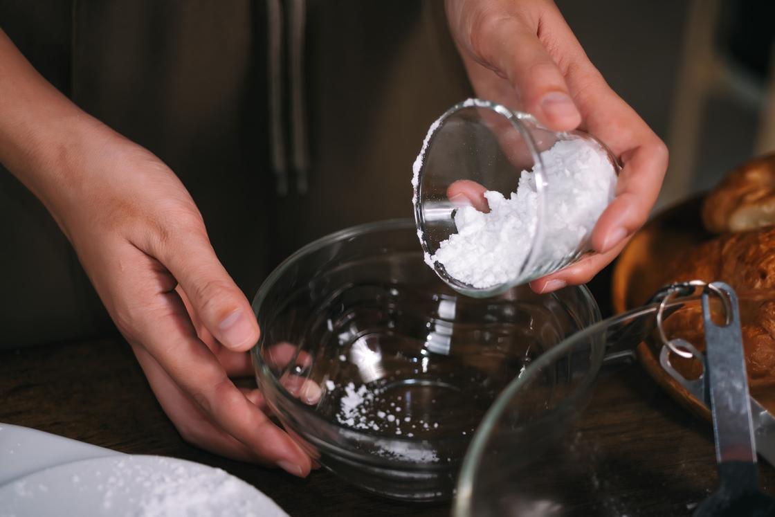 Соду высыпают из стакана в стеклянную миску