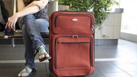 девушка с багажом сидит в аэропорту
