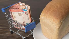 Пачка тенге лежит в миниатюрной корзине рядом с булкой хлеба