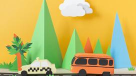 Инсталляция из бумажного такси, автобуса, которые едут по дороге. На фоне выставлены деревья треугольной формы и тучки на небе