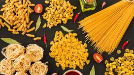На столе макароны разной формы: спагетти, бантики, рожки, спиральки,
