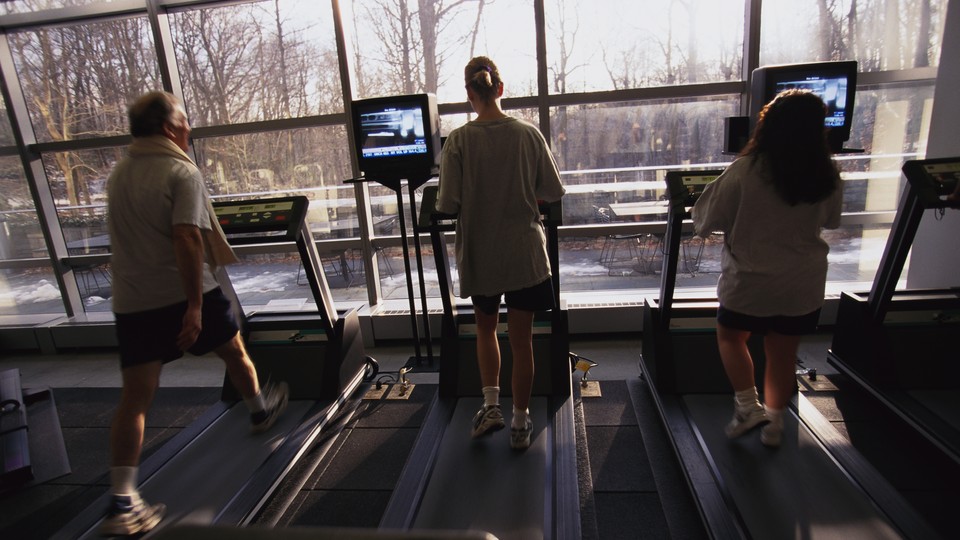 Three people run on treadmills.