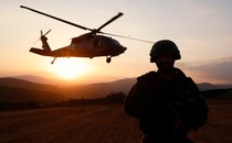 An Israeli soldier looks on as a military helicopter hovers.