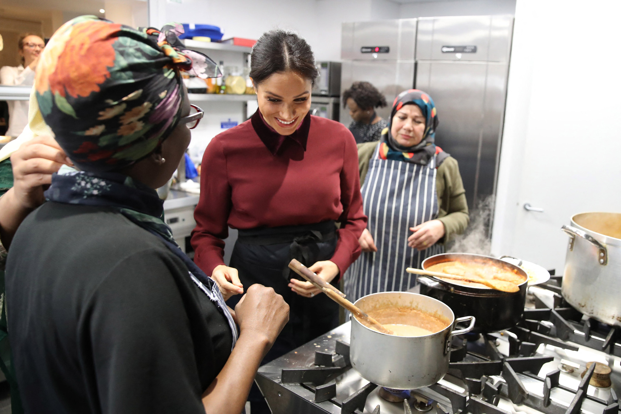Meghan, Duchess of Sussex (C) visits the Hubb Community Kitchen in London on November 21, 2018 to celebrate the success of their cookbook. The kitchen was set up by women affected by the Grenfell tower fire and Meghan, Duchess of Sussex wrote a foreword to the cookbook to help raise funds for the victims. (Photo by Chris Jackson / POOL / AFP)