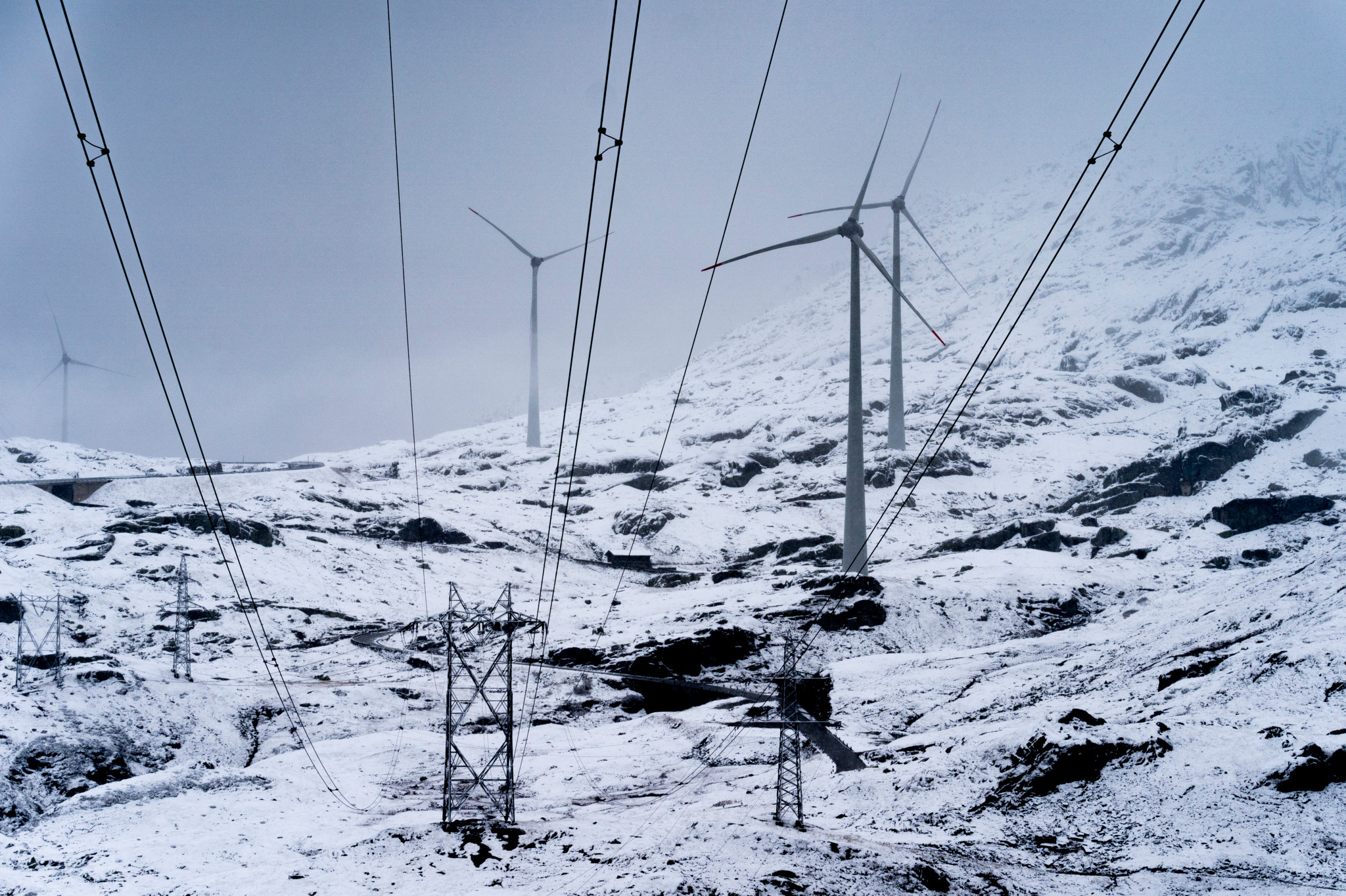 Eine Hochspannungsleitung und vier der fuenf Windkraftanlagen mit einem 98 Meter hohen Mast und einem Rotor mit einer Spannweite von 92 Metern, die sich auf dem Gotthardpass befinden, aufgenommen in einem Schneesturm am Freitag, 30. September 2022 .(KEYSTONE/Gaetan Bally)
