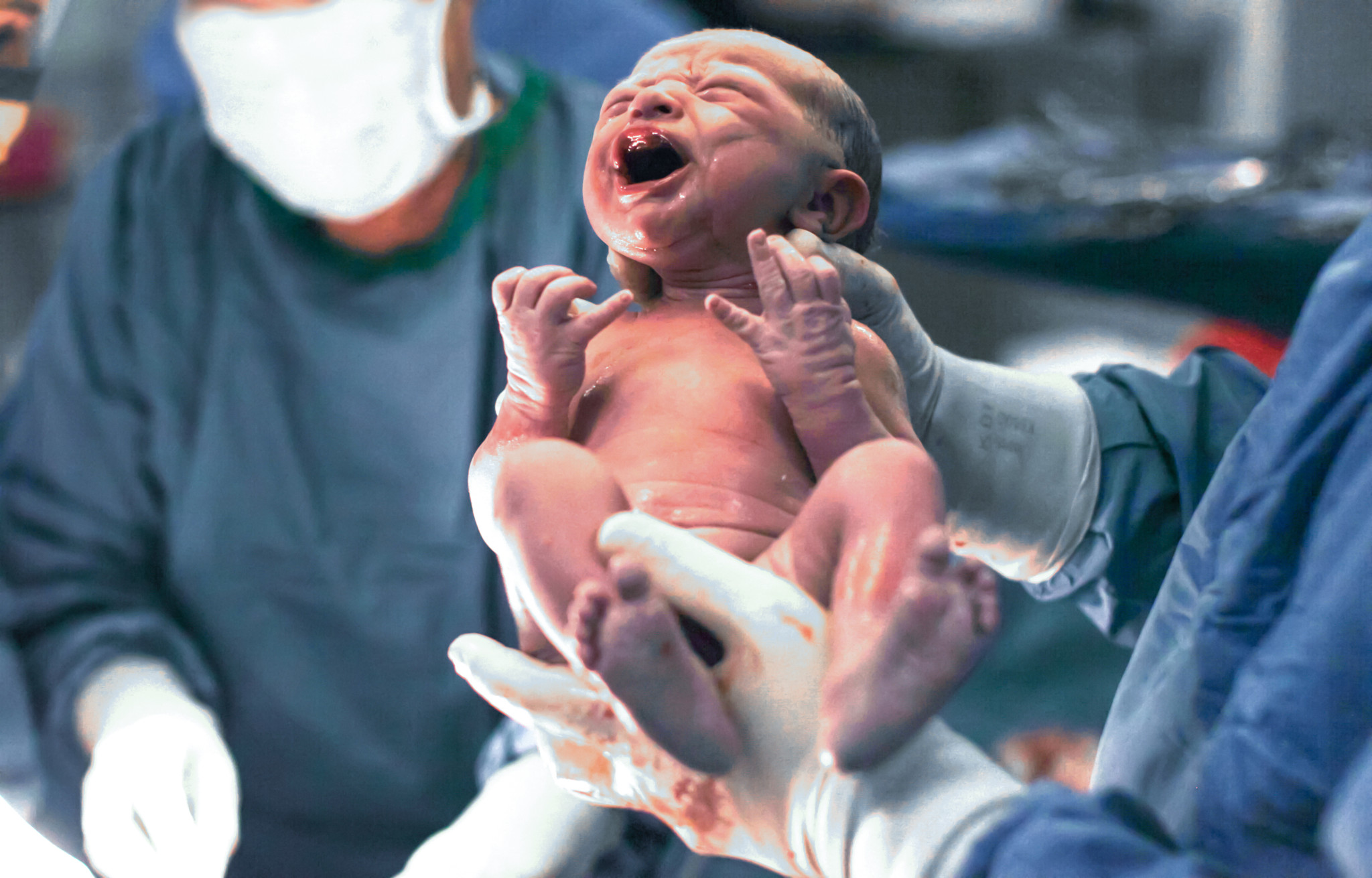 Doctors holding newborn baby boy.