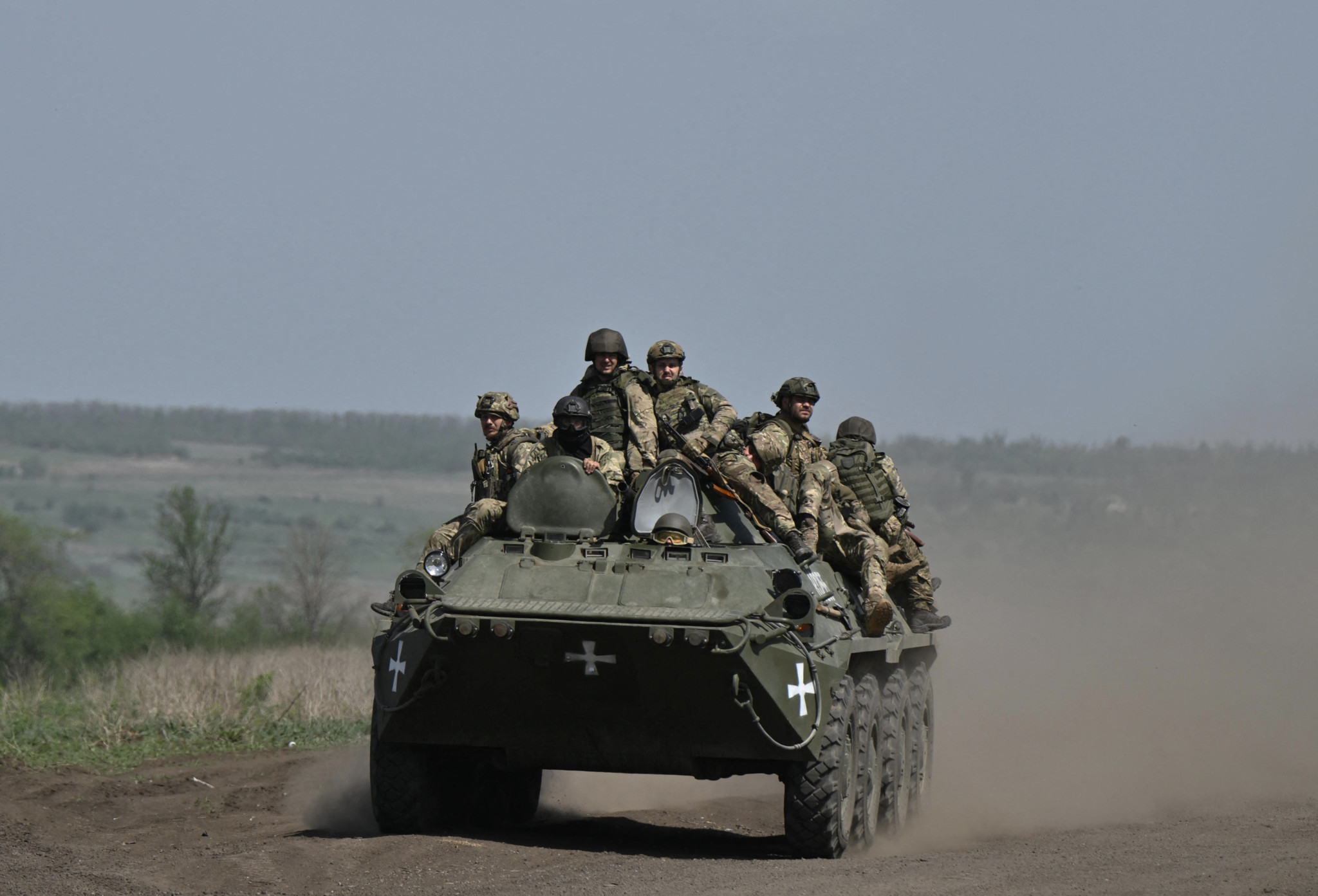 Ukrainian servicemen ride on an armored personnel carrier  (APC) in a field near Chasiv Yar, Donetsk region, on April 27, 2024, amid the Russian invasion of Ukraine. (Photo by Genya SAVILOV / AFP)