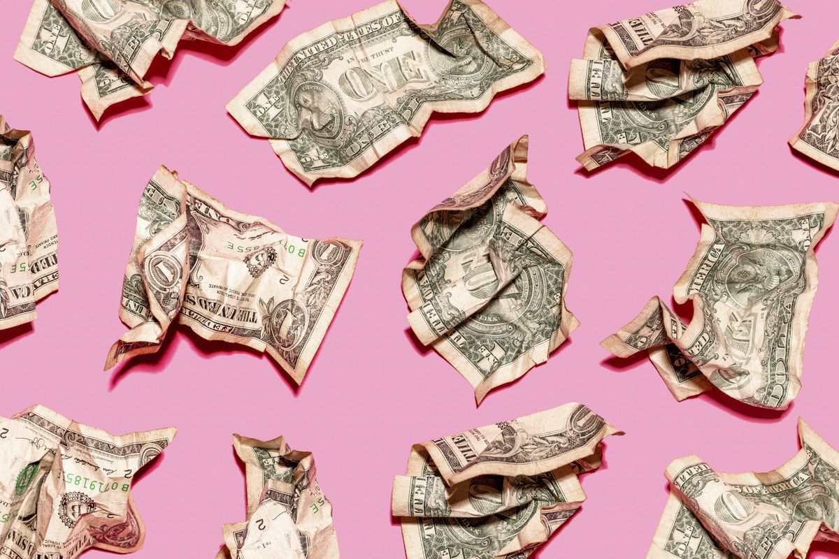 Crumpled dollar bills on a pink background