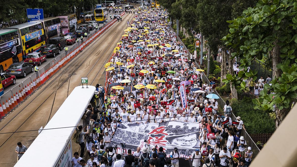 Protesters walk through Hong Kong with signs and yellow umbrellas. 