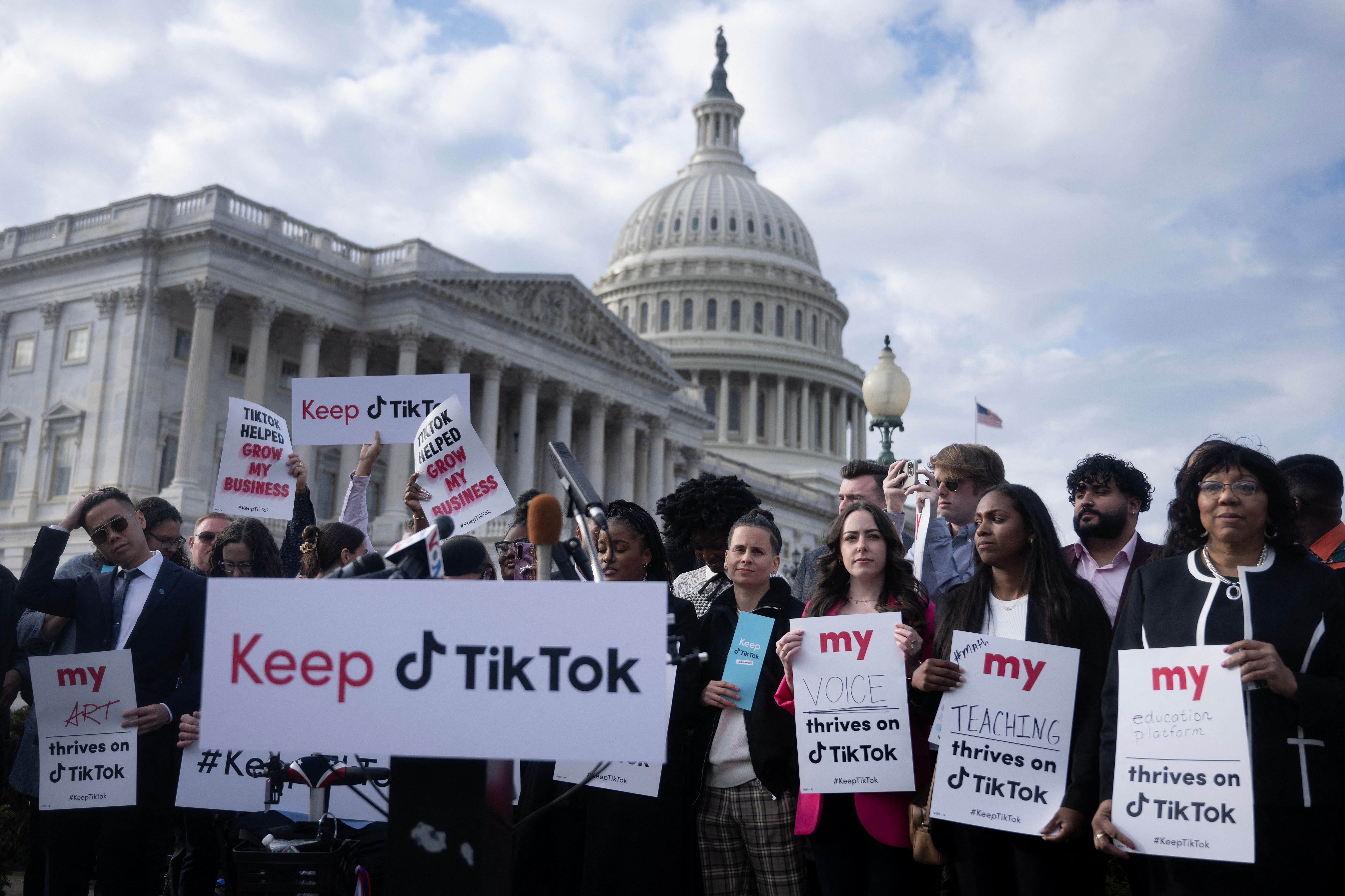 A group of protesters gathers in front of the US Capitol building, holding signs that support TikTok.