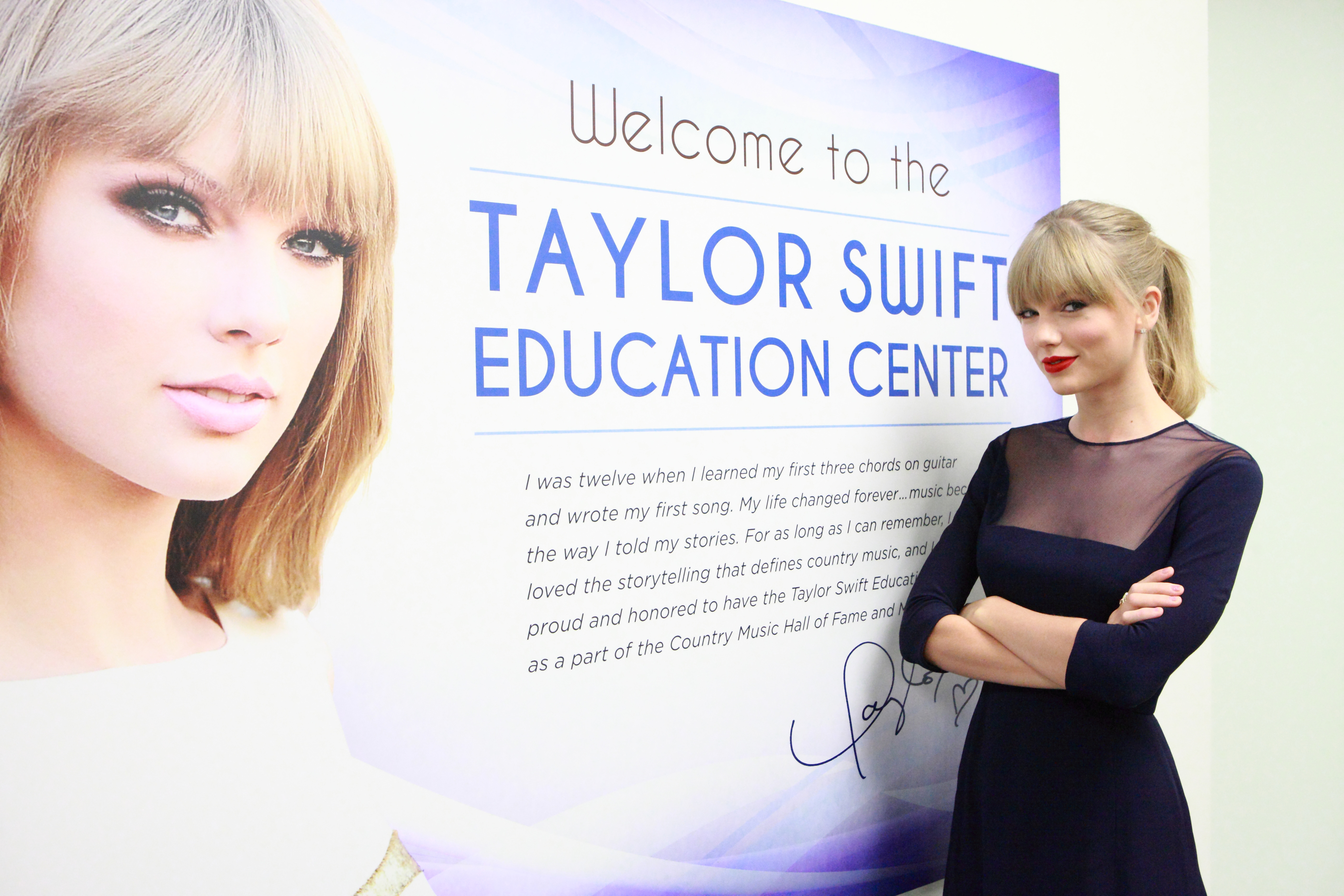 Taylor Swift in front of a sign for the Taylor Swift Education Center