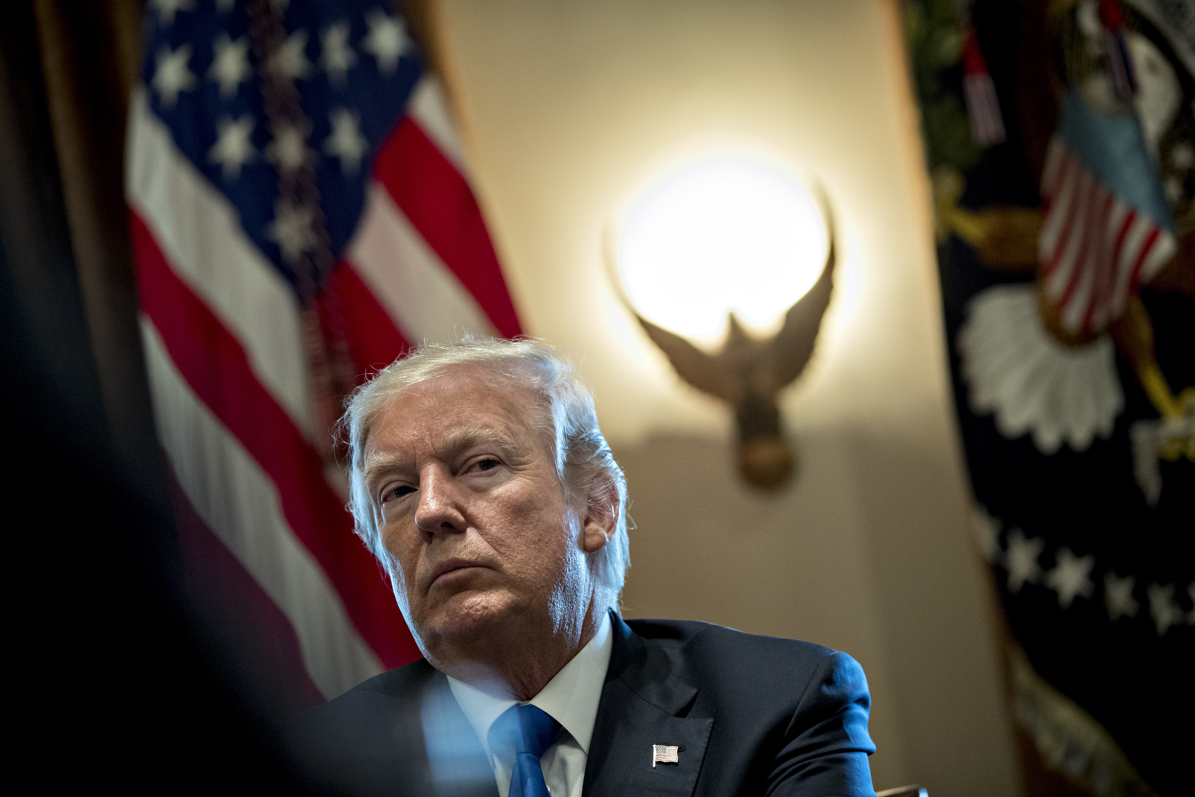 Trump looking stern with an American flag behind him. 